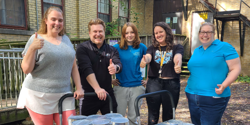 Five volunteers in front of the WWRC with dollies loaded with large cans of beans